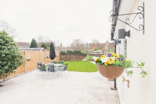 a patio with chairs and a basket of flowers at LYNNTON HOUSE Stunning 6 bed Town Centre House ALL with En-Suites Prime Location Tamworth in Tamworth