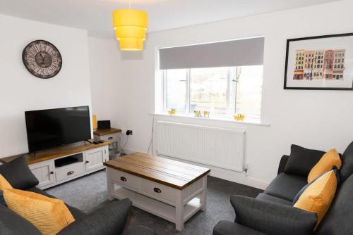 a living room with a couch and a tv and a table at Argyle House Stunning 2 Bed Town Centre Home from Home with Private Parking in Tamworth