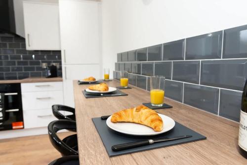 a table with two plates of croissants and glasses of orange juice at Argyle House Stunning 2 Bed Town Centre Home from Home with Private Parking in Tamworth