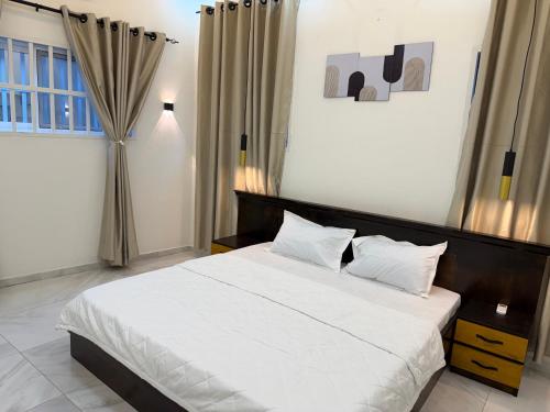 a bedroom with a bed with white sheets and a window at Appartement Kekely in Yovo Kopé