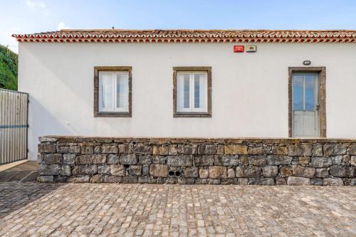 a house with a stone wall and windows at Casas do Forneiro - T1 in Nordeste
