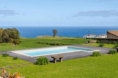 a swimming pool with a bench and the ocean at Casas do Forneiro - T1 in Nordeste