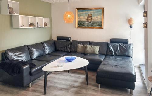 a living room with a black leather couch and a table at Awesome Home In Thyborøn With Wifi in Thyborøn
