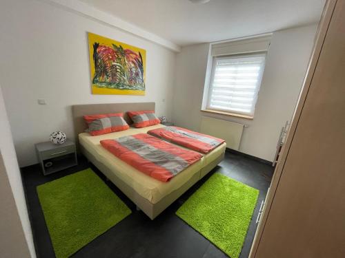 a bedroom with a bed and two green rugs at Ferienwohnung Karin in Losheim