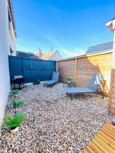 a backyard with two benches and a fence at Les Hirondelles B in Le Crotoy