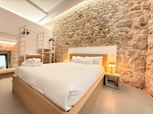 a bedroom with a large bed and a stone wall at Apartamento Calle Limón in Santander