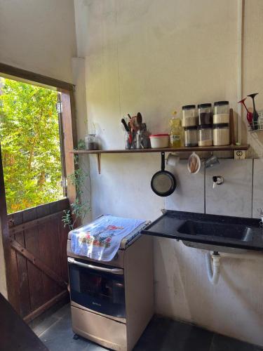 a kitchen with a stove and a sink and a window at Chalé do Ben in São Thomé das Letras