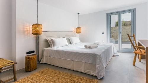 a white bedroom with a large bed and a table at Double Pool Villa Ι in Kampos Paros