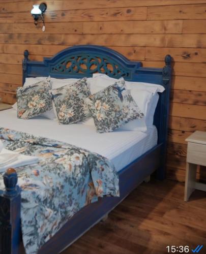 ein Bett mit blauem Kopfteil und Kissen darauf in der Unterkunft Kurfal Hotel in Agva