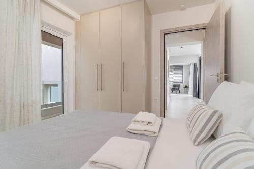 a white bedroom with a large bed with two towels at M P A Luxury Apartment Α2 in Agios Nikolaos