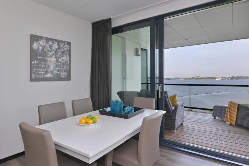 une salle à manger avec une table blanche et un balcon dans l'établissement Veerse Muze, à Kamperland