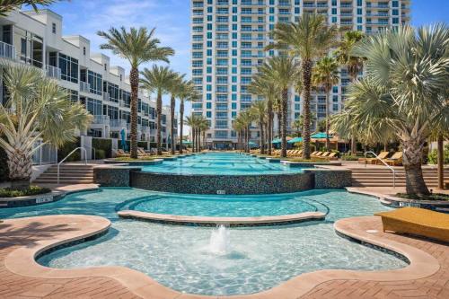a swimming pool with palm trees and a fountain at Sapphire Beach - Breathtaking 26th Floor Views in South Padre Island