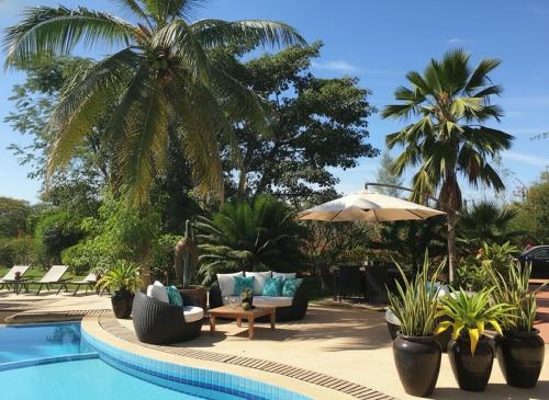 a resort with a pool with palm trees and chairs at Bandam Lodge in Ngaring