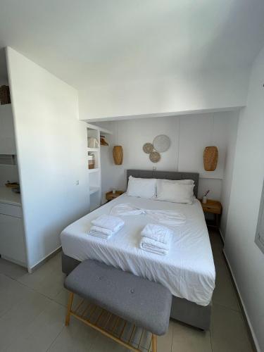 a bedroom with a white bed and a chair at CHORA NEST KYTHNOS in Kithnos