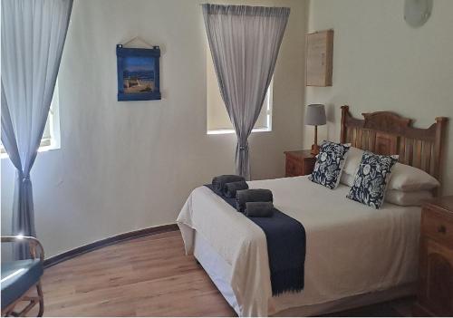 a bedroom with a bed and two windows at Outeniqua Strandwoonstel in Great Brak River
