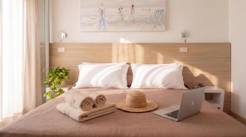 a bed with a hat and a laptop on it at Igea Spiaggia Home Holiday in Bellaria-Igea Marina