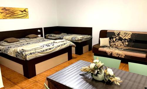 a room with two beds and a table with flowers on it at Bungalovy CLASSIC & Wellness Podhájska - Adults Only in Podhájska