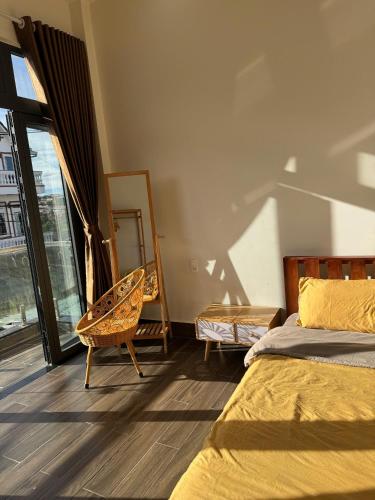a bedroom with a bed and a chair and a window at La Maison DaLat Home in Ấp Kim Thạch