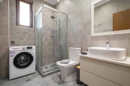 a bathroom with a toilet and a sink and a washing machine at Myrina Concept in Myrina