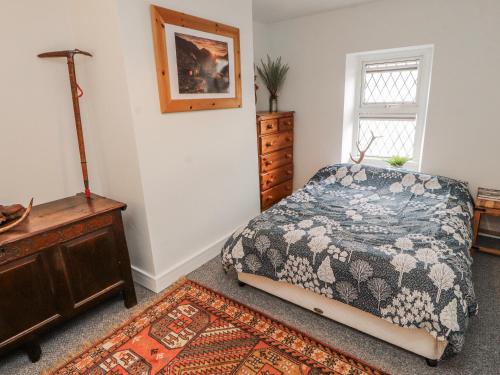a bedroom with a bed and a dresser and a window at 25 Low Seaton in Workington