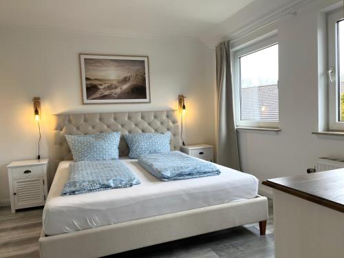 a white bedroom with a bed with blue pillows at Ferienhaus Haffliebe in Scharbeutz