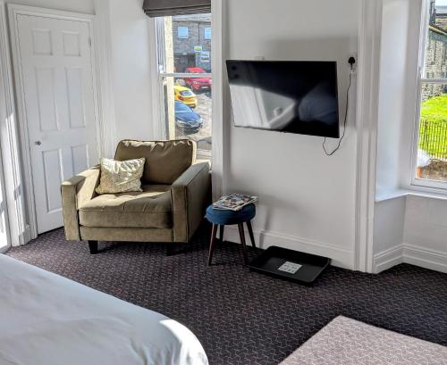 a room with a bed and a chair and a tv at The White Hart Inn, Hawes in Hawes