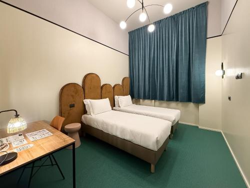 a room with two beds and a desk and a table at QUO Milano in Milan