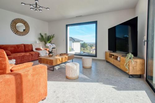 a living room with a couch and a flat screen tv at BELLEVUE 2, piscine, jacuzzi, sauna in Champcevinel