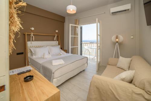 a bedroom with a bed and a living room with a couch at Archontiko Seaside Hotel-Beachfront Blue Experience in Platanias