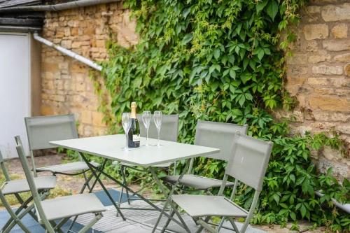 a white table and chairs with wine bottles and glasses at Redesdale View, High Street with Private Garden in Moreton in Marsh
