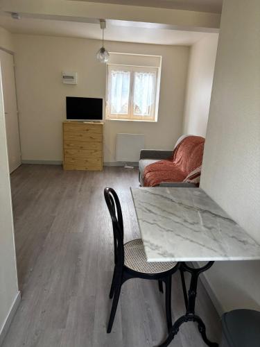 a living room with a table and a couch at Sur Egletons - Le Cocon Egletons in Égletons
