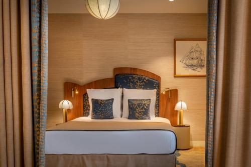 a bedroom with a bed with blue and white pillows at Hôtel La Bourdonnais by Inwood Hotels in Paris