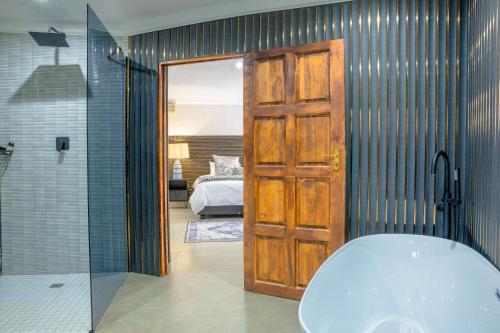 a bathroom with a bath tub and a bedroom at Apple Blossom Hotel Portfolio in Roodepoort