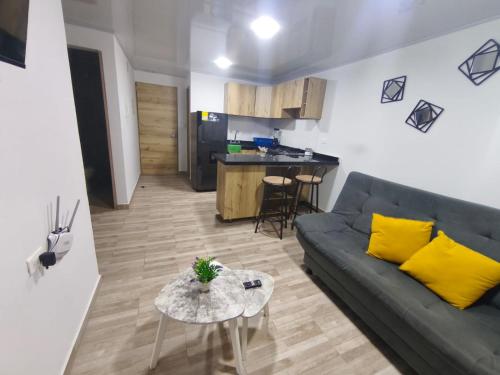 a living room with a couch and a table and a kitchen at Apartahotel y casa de campo AMARU in San Gil