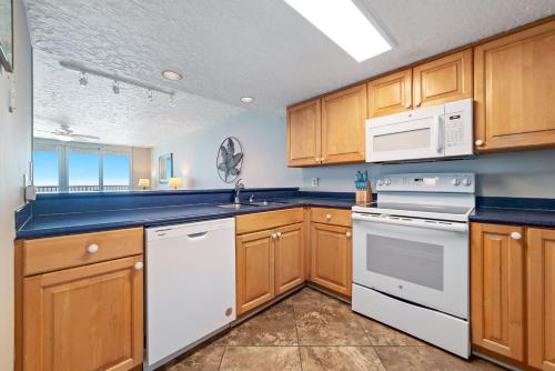 a kitchen with wooden cabinets and white appliances at Romar Tower Unit 9D in Orange Beach