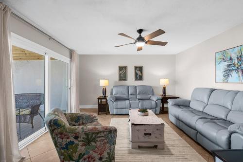 a living room with blue couches and a ceiling fan at Boardwalk Unit A18 in Pensacola Beach