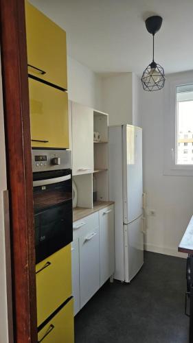 a kitchen with yellow cabinets and a refrigerator at T3 idéalement situé in Mérignac