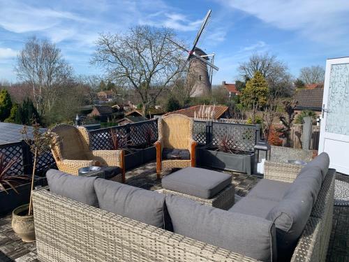 a patio with a couch and chairs and a windmill at B&B Petit Chateau - Rust en Charme Nabij Gent, Brugge en de Zeeuwse kust in Biervliet