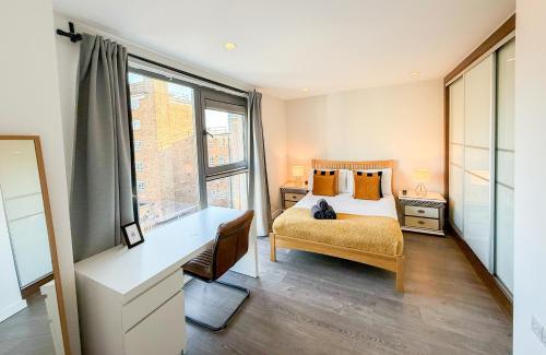 a bedroom with a bed and a desk and a window at Contemporary Apartments with Private Balconies in Hoxton near Shoreditch, Old Street, Islington by Staylio Ltd in London