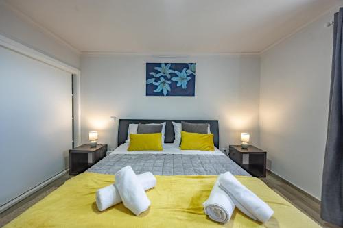 a bedroom with a large bed with two yellow pillows at A Quintinha by YOUR KEY MADEIRA in Santa Cruz