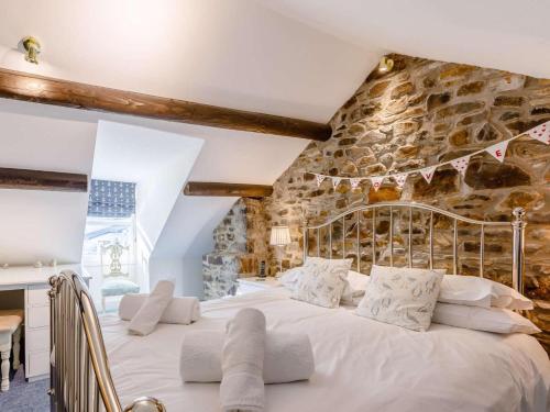 a bedroom with a large bed with a stone wall at 3 Bed in Bideford oc-57804 in Appledore