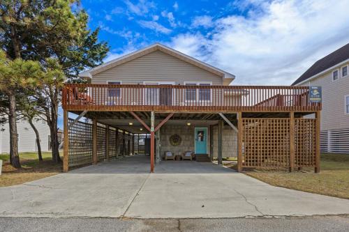 a house with a deck on a driveway at 5085 - Knapp's at the Beach in Kill Devil Hills