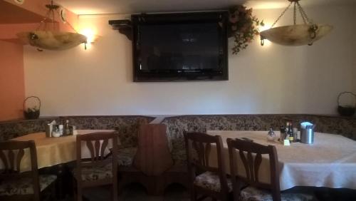 a dining room with two tables and a tv on the wall at Penzion Pod Boubínem in Kubova Huť