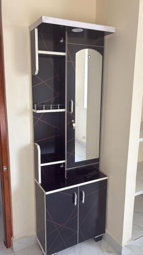 a black cabinet with a mirror in a bathroom at Bhuvanavasigal alayam in Tiruvannāmalai