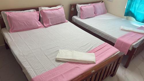 two beds in a room with pink and white sheets at Bhuvanavasigal alayam in Tiruvannāmalai