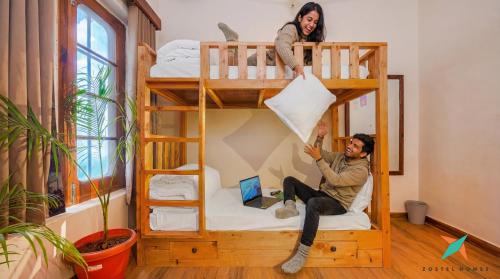 a man and a woman sitting in a bunk bed at Zostel Homes Khajjiar in Chamba