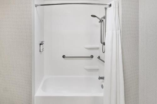 a bathroom with a shower with a white shower curtain at Holiday Inn Express Kansas City - at the Legends! by IHG in Kansas City