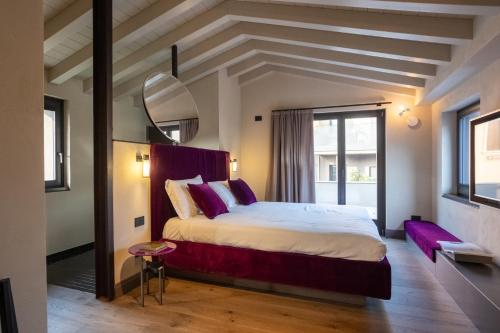 a bedroom with a large bed with purple pillows at Relais Villa Borghetto - Adults only in Valeggio sul Mincio