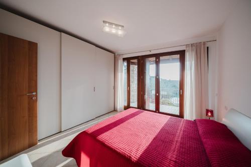 a bedroom with a red bed with a large window at Villetta Le Scaje in Torri del Benaco