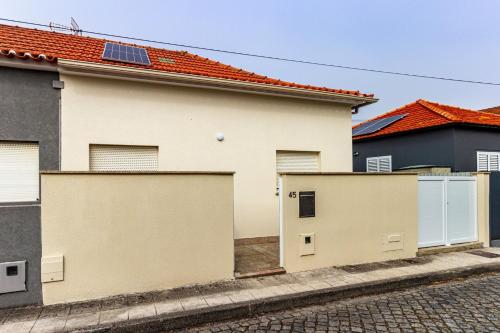 a white house with two garage doors on a street at Guest H4U - Garden & Beach Mindelo in Mindelo